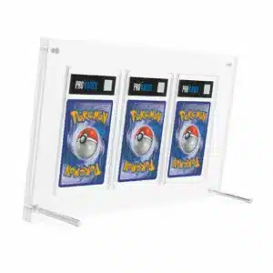 Protection cartes Pokémon PCA (99,9%) est un coffret transparent de protection pour cartes Pokémon. On y voit 3 cartes gradées par l'entreprise PCA de dos. Le support repose sur deux petites barres rondes en métal.