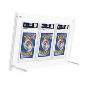 Protection acrylique pour 3 cartes PSA, résistante aux UV (99,9%) est un coffret transparent de protection pour cartes Pokémon. On y voit 3 cartes gradées par l'entreprise PSA de dos. Le support repose sur deux petites barres rondes en métal.