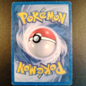 dos de la carte Energie Obscurité 103/113. Carte du TCG Pokémon issue de la série Espèces Delta du bloc EX (EX: Espèces DELTA) parue le 09/06/2006. Carte Energie. Rare. Illustrateur: Milky Isobe. L'illustration du verso de cette carte représente une Pokéball en son centre. Il s'agit s'une sphère bicolore: rouge dans sa moitié supérieure et blanche pour la moitié inférieure. Le Logo Pokémon est répété au-dessus et en dessous de la Pokéball, en jaune. Le fond de la carte est de couleur bleue.