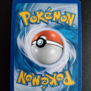 dos de la carte Sidérella (reverse) 57/124. Carte du TCG Pokémon issue de la série Dragons Exaltés bloc Noir et Blanc (NB04), parue le 10/11/2012. Carte Pokémon Niveau 1 de type Psy, évolution de Mesmérella, Rare. Illustrateur: Akira Komayama. L'illustration du verso de cette carte représente une Pokéball en son centre. Il s'agit s'une sphère bicolore: rouge dans sa moitié supérieure et blanche pour la moitié inférieure. Le Logo Pokémon est répété au-dessus et en dessous de la Pokéball, en jaune. Le fond de la carte est de couleur bleue.