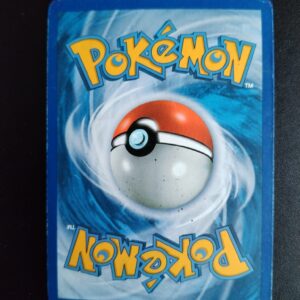 dos de la carte Trioxhydre (holo) 98/124. Carte du TCG Pokémon issue de la série Dragons Exaltés bloc Noir et Blanc (NB06), parue le 10/11/2012. Carte Pokémon Niveau 2 de type Dragon, évolution de Diamat, Rare. Illustrateur: Naoki Saito. L'illustration du verso de cette carte représente une Pokéball en son centre. Il s'agit s'une sphère bicolore: rouge dans sa moitié supérieure et blanche pour la moitié inférieure. Le Logo Pokémon est répété au-dessus et en dessous de la Pokéball, en jaune. Le fond de la carte est de couleur bleue.