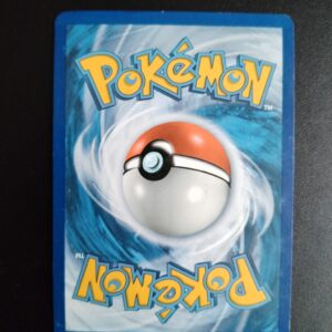 dos de la carte Grolem d'Alola (holo) 42/145. Carte du TCG Pokémon issue de la série Gardiens Ascendants du bloc Soleil et Lune (SL02, SL: Gardiens Ascendants), parue le 13/05/2017. Carte Pokémon de Niveau 2 de type Electric, évolution de Gravalanch d'Alola. Rare. Illustrateur: Shin Nagasawa. L'illustration du verso de cette carte représente une Pokéball en son centre. Il s'agit d'une sphère bicolore: rouge dans sa moitié supérieure et blanche pour la moitié inférieure. Le Logo Pokémon est répété au-dessus et en dessous de la Pokéball, en jaune. Le fond de la carte est de couleur bleue.