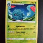 Bouldeneu (reverse) 8/147. Carte du TCG Pokémon issue de la série Ombres Ardentes du bloc Soleil et Lune (SL03, SL: Ombres Ardentes), parue le 19/08/2017. Carte Pokémon de Niveau 1 de type Plante, évolution de Saquedeneu. Rare. Illustrateur: tetsuya Koizumi. L'illustration représente une créature à la peau violette couverte de long cheveux gris-bleus. Elle évolue sur une plaine dans la nuit.