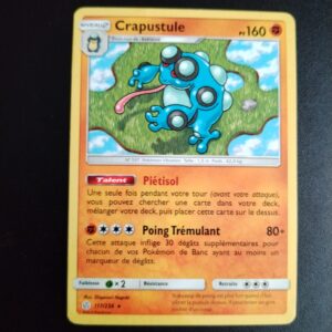 Crapustule 117/236. Carte du TCG Pokémon issue de la série Eclipse Cosmique du bloc Soleil et Lune (SL12, SL: Eclipse Cosmique), parue le 01/11/2019. Carte Pokémon de Niveau 2 de type Combat, évolution de Batracné. Rare. Illustrateur: Shigenori Negishi. L'illustration représente un gros crapaud bleu debout sur ses pattes arrières.