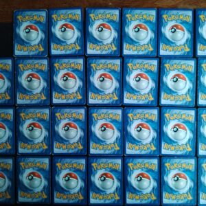 dos des cartes du lot de 27 cartes communes et peu communes en états variables/mauvais état. Cartes du TCG Pokémon issues de la série Déchaînement du bloc HeartGold SoulSilver (HS: Déchaînement), parue le 20/08/2010. Insolourdo 29/95 (illustrateur: Takashi Yamaguchi), Ptitard 58/95 (illustrateur: Naoyo Kimura), Vortente 46/95 (illustrateur: Wataru Kawahara), 2X Ceribou 47/95 (illustrateur: match), 2X Natu 55/95 (illustrateur: sui), Nosferapti 70/95 (illustrateur: Kawayoo), Goupix 68/95 (illustrateur: Hajime Kusajima), Férosinge 53/95 (illustrateur: Sachiko Adachi), Embrylex 51/95 (illustrateur: Kouki Saitou), 2X Remoraid 59/95 (illustrateur: Ken Sugimori), Récupérateur d'énergie 74/95 (illustrateur: Wataru Kawahara), 2X Bavardage du maître 73/95 (illustrateur: Kouki Saitou), 2X Encouragements hystériques 71/95 (illustrateur: Kouki Saitou), 2X Herbe sauveuse 79/95 (illustrateur: Hideaki Hakozaki), 2X PlusPower 80/95 (illustrateur: Takashi Yamaguchi), Questionnaire d'interview 77/95 (illustrateur: Kouki Saitou), 4X Réglages techniques 75/95 (illustrateur: Kouki Saitou). L'illustration du verso de ces cartes représente une Pokéball en son centre. Il s'agit s'une sphère bicolore: rouge dans sa moitié supérieure et blanche pour la moitié inférieure. Le Logo Pokémon est répété au-dessus et en dessous de la Pokéball, en jaune. Le fond de la carte est de couleur bleue.