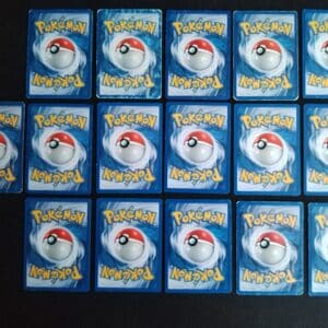 Dos du Lot de 16 cartes communes et uncos en mauvais état (états variables selon les cartes). Carte du TCG Pokémon issues de la série Créateurs de Légendes du bloc EX (EX: Créateurs de Légendes) parue le 01/09/2006. Le lot comprend 2 exemplaires de Gravalanch 34/92 (Illustrateur: Sumiyoshi Kizuki), Chetiflor 49/92 (Illustrateur: Midori Harada), Galekid 48/92 (Illustrateur: Miki Tanaka), Fouinar 33/92 (Illustrateur: Tomokazu Komiya), Loupio 50/92 (Illustrateur: Sachiko Adachi), 2 exemplaires de Coquiperl 51/92 (Illustrateur: Sachiko Adachi), Fossile Griffe 78/92 (Illustrateur: Ryo Ueda), Tadmorv 54/92 (Illustrateur: Tomokazu Komiya), Machoc 57/92 (Illustrateur: Yukiko Baba), Lilia 56/92 (Illustrateur: Atsuko Nishida), Skitty 64/92 (Illustrateur: Satosho Ohta), Voltorbe 68/92 (Illustrateur: Midori Harada), Racaillou 53/92 (Illustrateur: Miki Tanaka), Vibraninf 46/92 (Illustrateur: Atsuko Nishida). Sur l'image on distingue 16 cartes alignées sur 3 rangées. Les cartes sont présentées côté verso. L'illustration du verso de chaque carte représente une Pokéball en son centre. Il s'agit s'une sphère bicolore: rouge dans sa motié supérieure et blanche pour la moitié inférieure. Le Logo Pokémon est répété au-dessus et en dessous de la Pokéball, en jaune. Le fond de la carte est de couleur bleue.