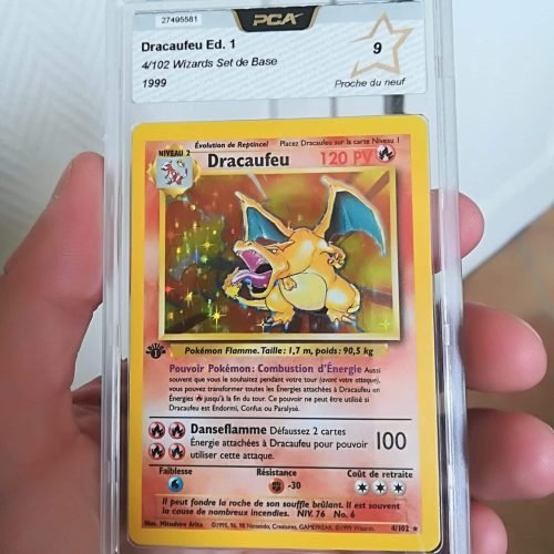 Charizard. On voit une carte gradée par PSA du JCC Pokémon. C'est la carte dracaufeu 1ere édition qui a obtenue la note de 9. Elle est présentée protégée par un cadre en plexiglass.